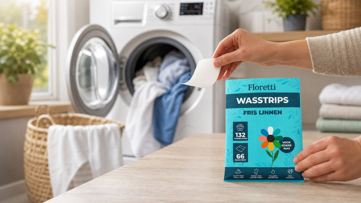 Hand houdt een Floretti wasstrip boven het pak Fris Linnen bij een geopende wasmachine